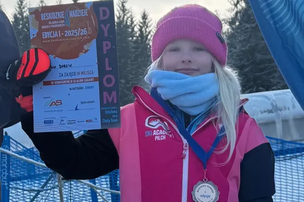 Na zdjęciu dziewczynka z dyplomem i medalem na szyji