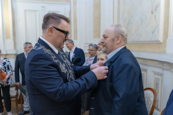 Na zdjęciu stojący ludzie 