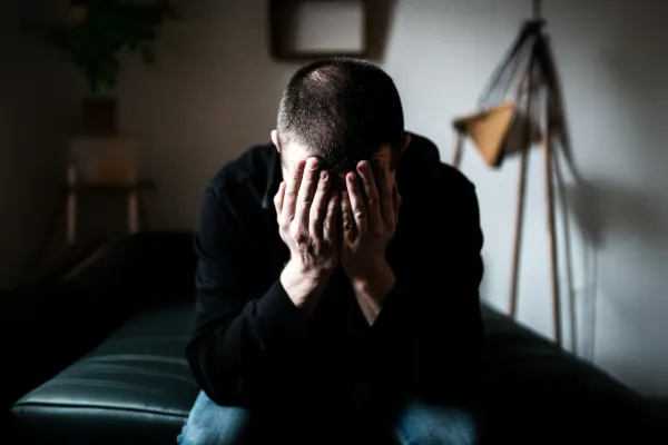 Na zdjęciu mężczyzna zakrywający twarz dłońmi