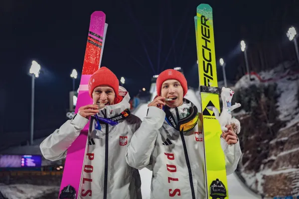 Na zdjęciu stojący ludzie 