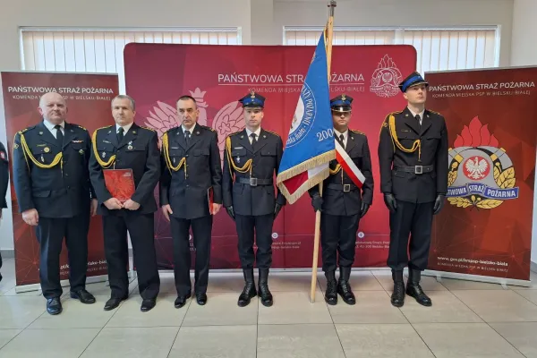 Na zdjęciu stojący ludzie 