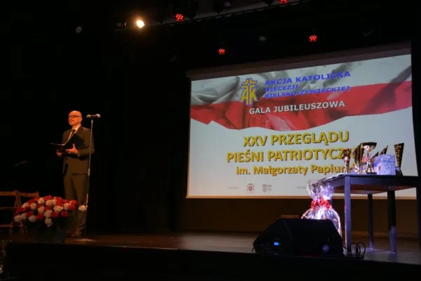 Na zdjęciu stojący ludzie 