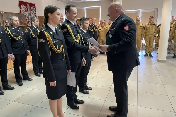 Na zdjęciu stojący ludzie 