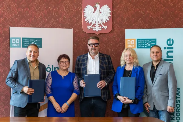 Na zdjęciu stojący ludzie 