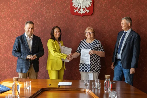 Na zdjęciu stojący ludzie 