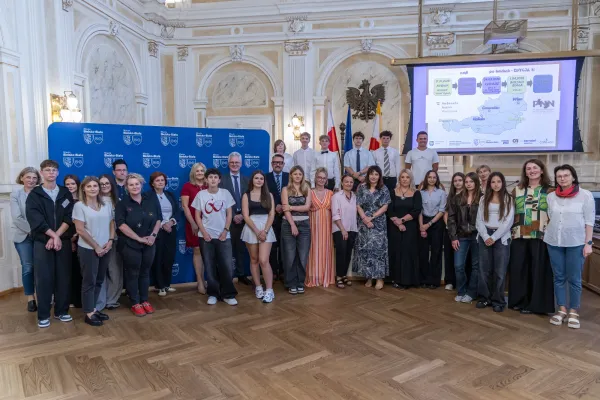 Na zdjęciu stojący ludzie 