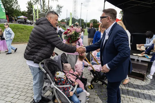 Na zdjęciu stojący ludzie 