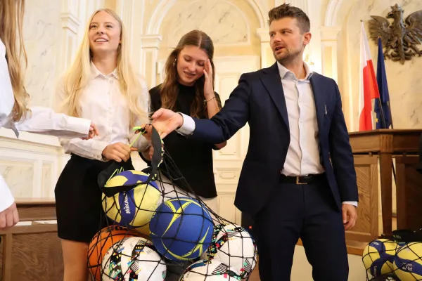 Na zdjęciu stojący ludzie 