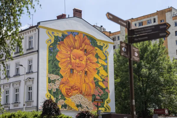 Na zdjęciu mural przedstawiający postać dziecka-kwiatu na kwitnącej łące