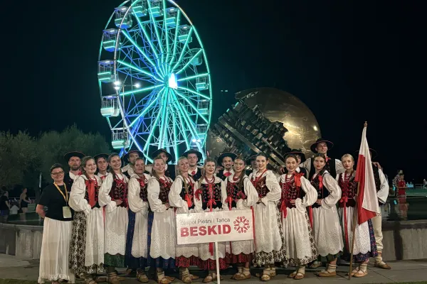 Na zdjęciu stojący ludzie 