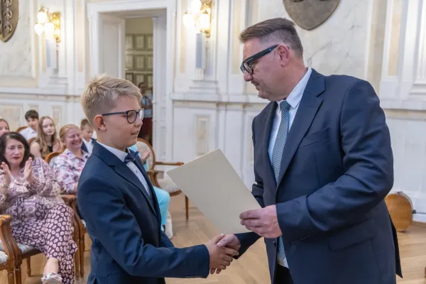 Na zdjęciu prezydent wręcza stypendium uczniowi podstawówki 