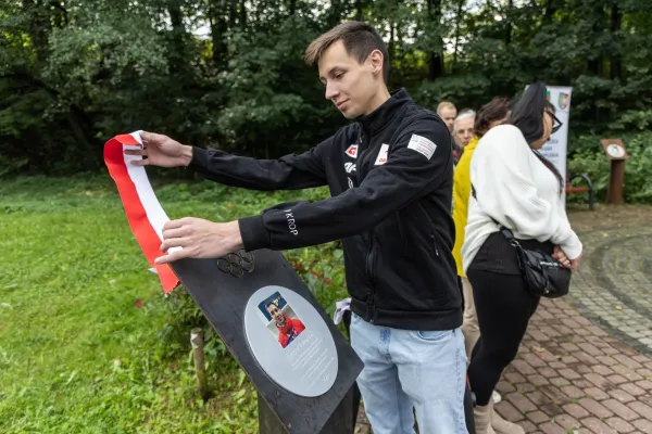 Na zdjęciu stojący ludzie 