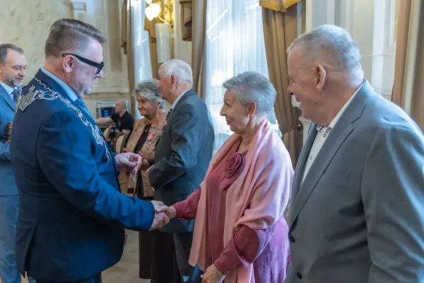 Na zdjęciu stojący ludzie 