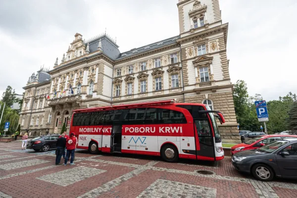 Na zdjęciu biało-czerwony ambulans przed historycznym budynkiem