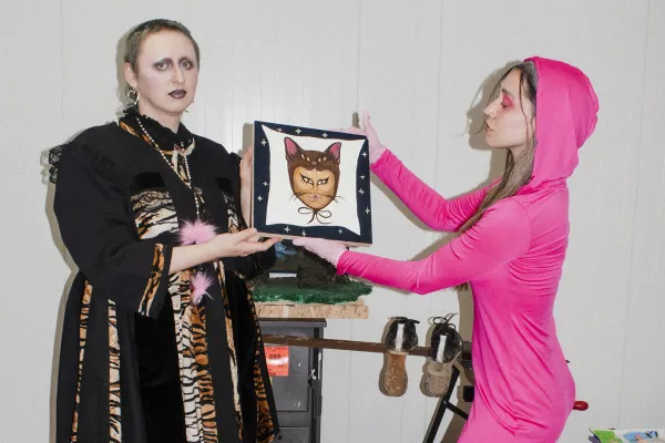 Na zdjęciu dwie osoby trzymające obrazek przedstawiający głowę kota