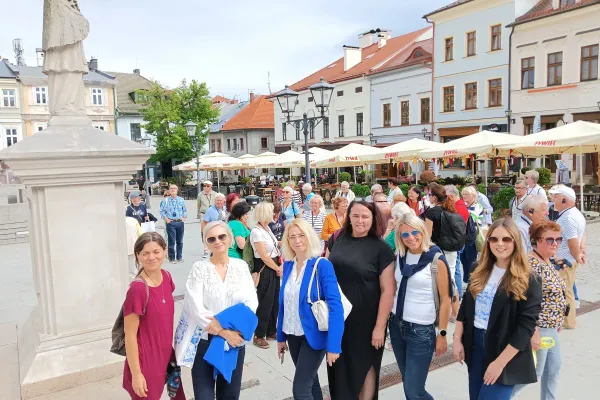 Na zdjęciu stojący ludzie 