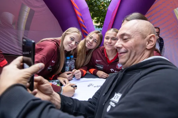 Na zdjęciu stojący ludzie 