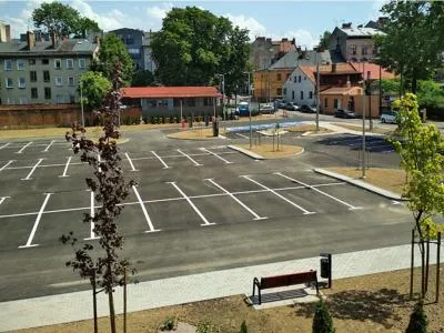 Zdjęcie przedstawiające pusty, nowo wybudowany parking z wyznaczonymi miejscami postojowymi.