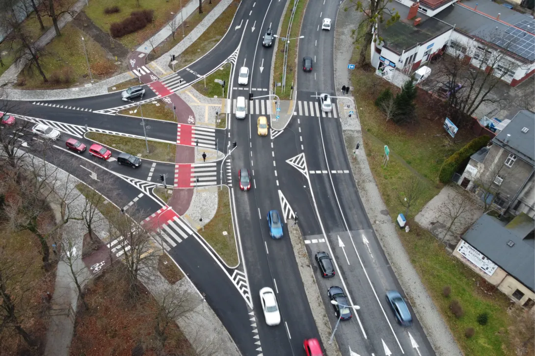 Zdjęcie przedstawiające duże skrzyżowanie drogowe liczne samochody poruszające się pod drodze z lotu ptaka.